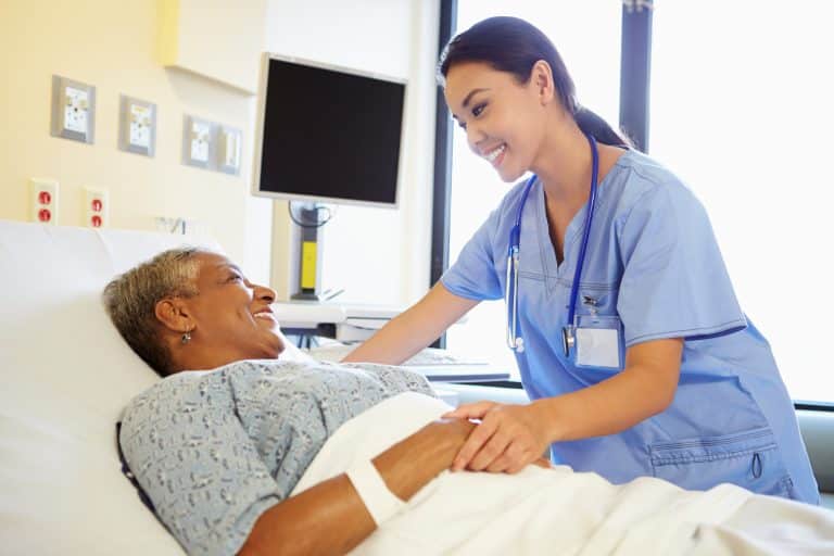 Nurse checking on older woman patient after surgery.