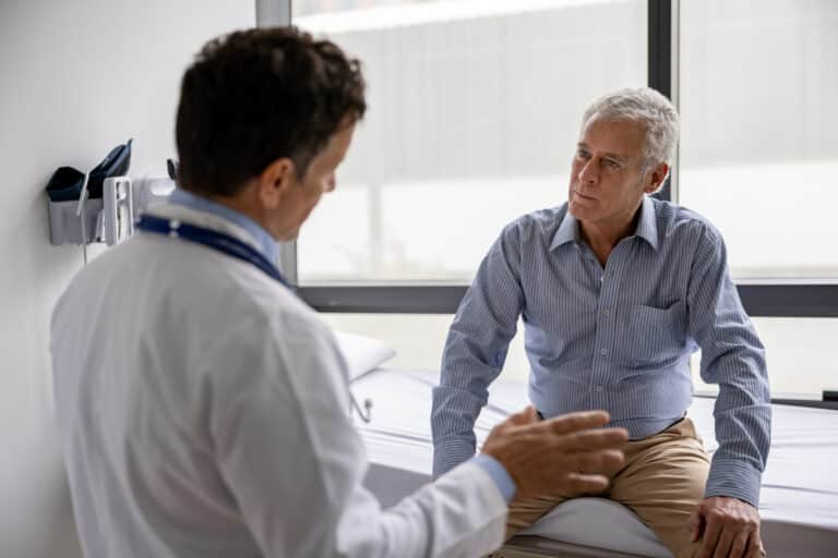 Doctor talking to a patient in a consultation at his office practice - healthcare and medicine concepts