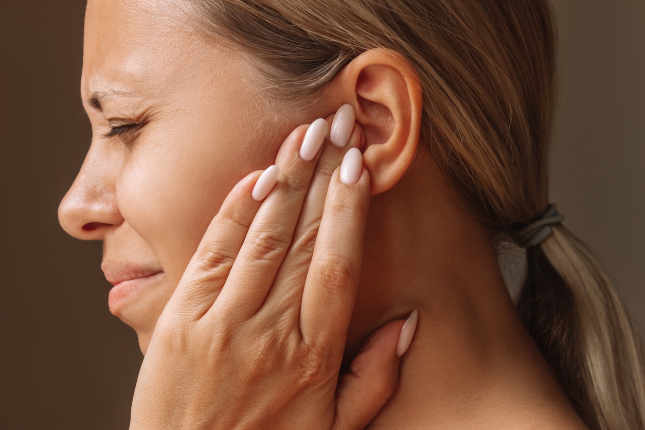 Woman with tinnitus holding her left ear