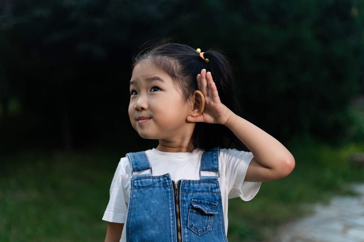 Young girl holds hand behind ear