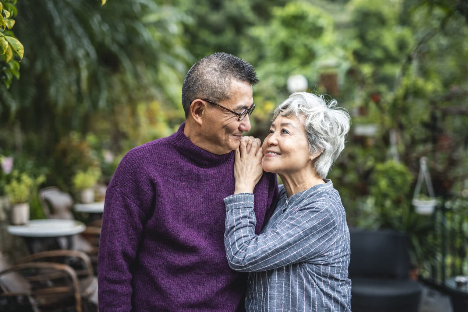 Happy older couple hugging while on a walk through a public garden.
