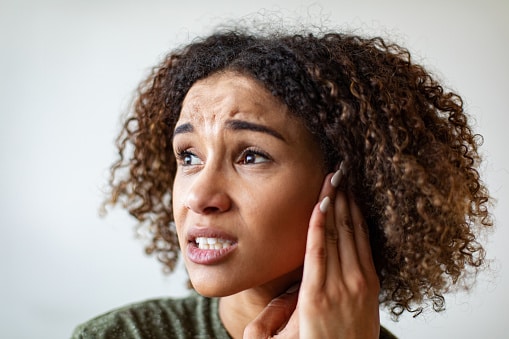 Woman holding her ear struggling to hear and feeling ear pain.
