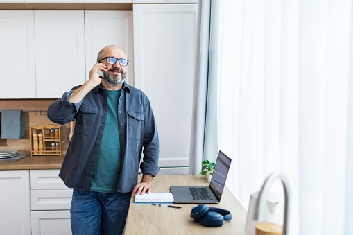 Happy man on the phone with his audiologist's office, scheduling a hearing aid maintenance appointment.
